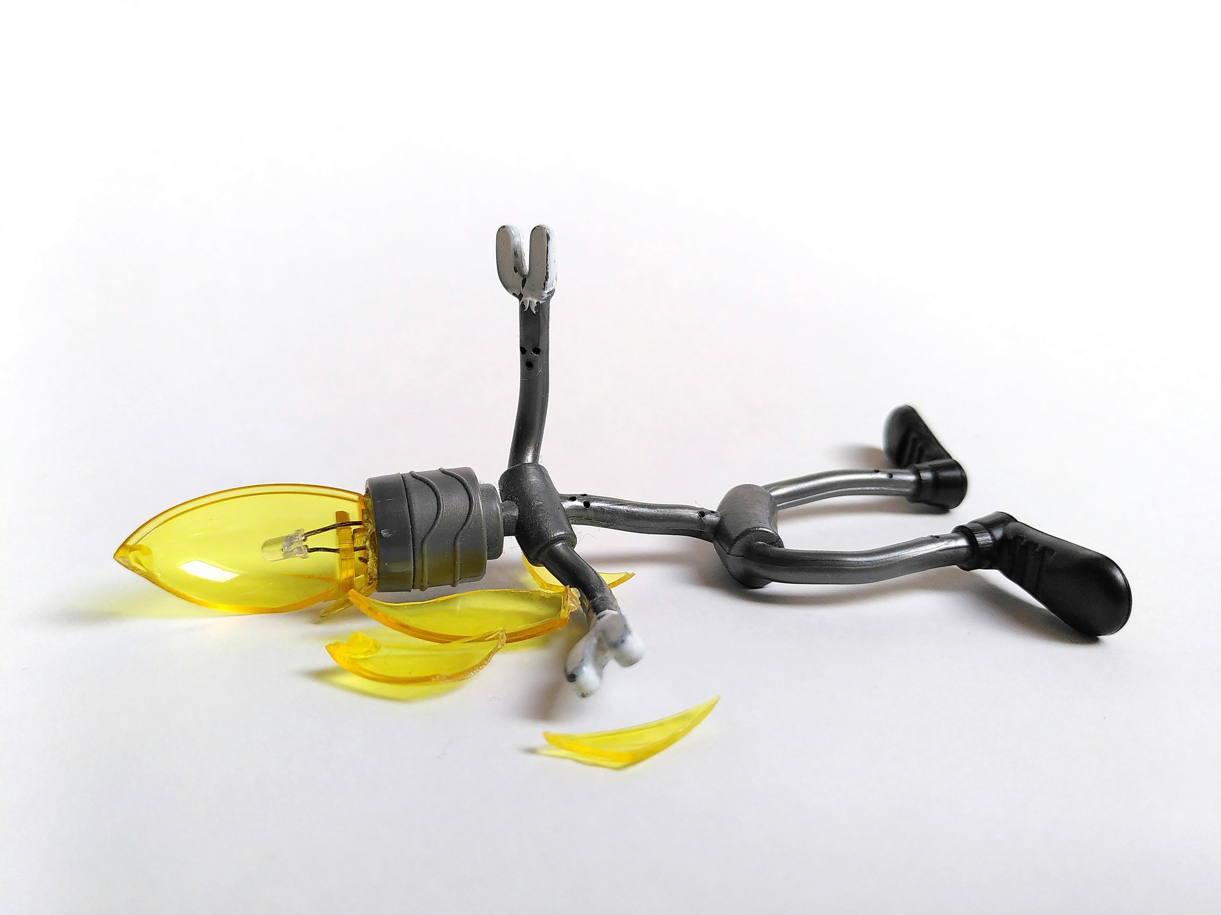 A stock-y image of a "robot" figurine, laying "dead" on the ground. Its head is a broken lightbulb.