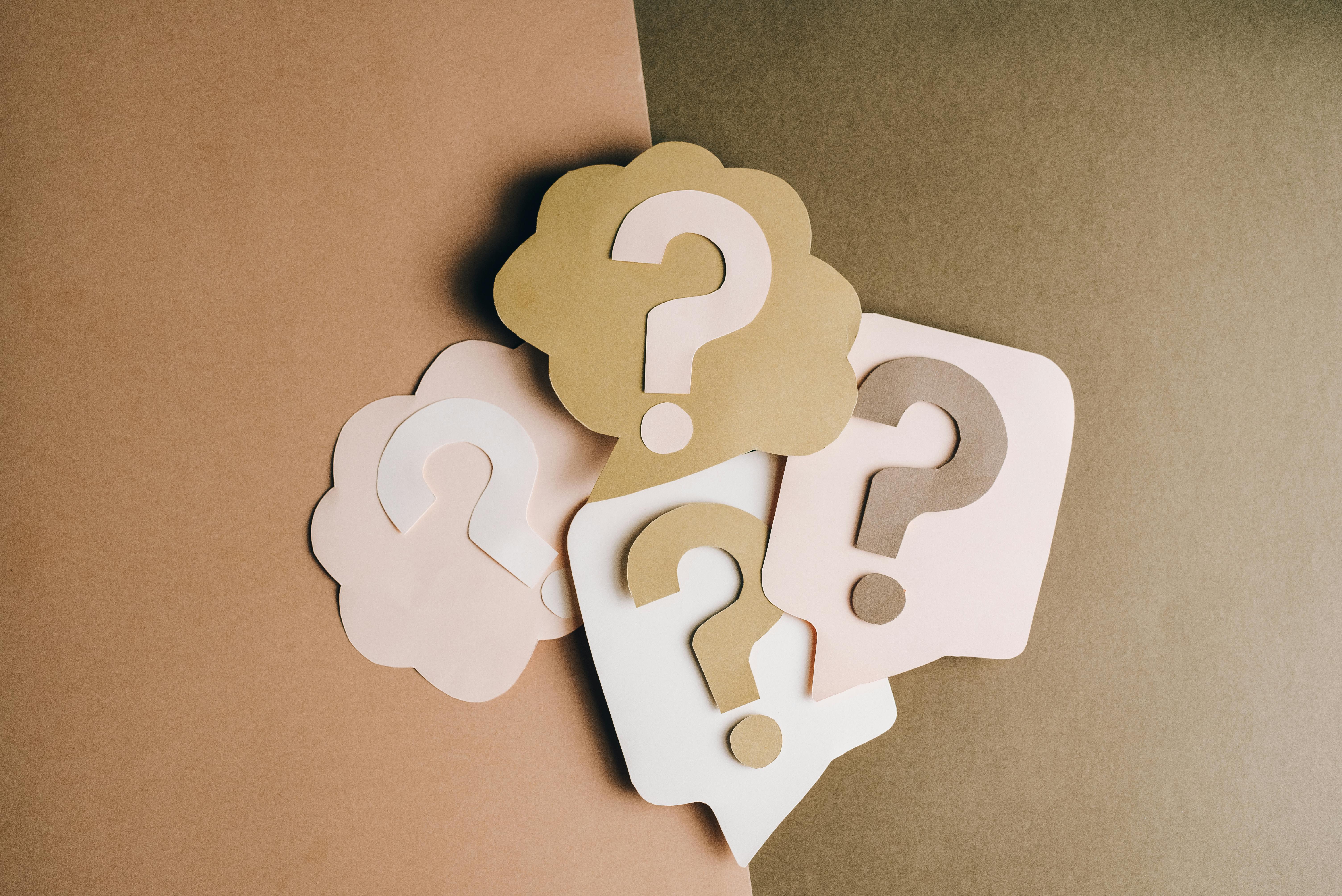 A paper-collage style image of a bunch of question marks.